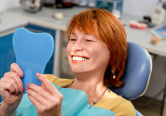 Red Head woman smiling into a mirror at the dentist